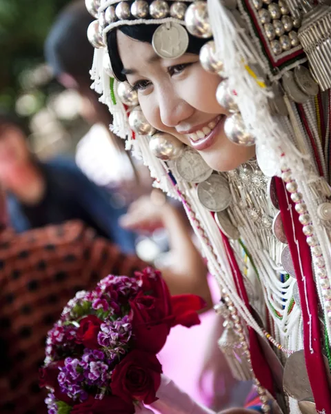 A smiling woman in a silver-beaded headdress holding flowers, Chiang Rai, Thailand