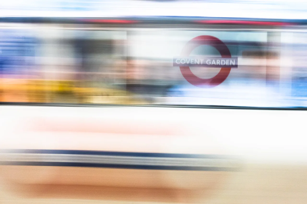 A Tube train blurring past the Covent Garden sign, London