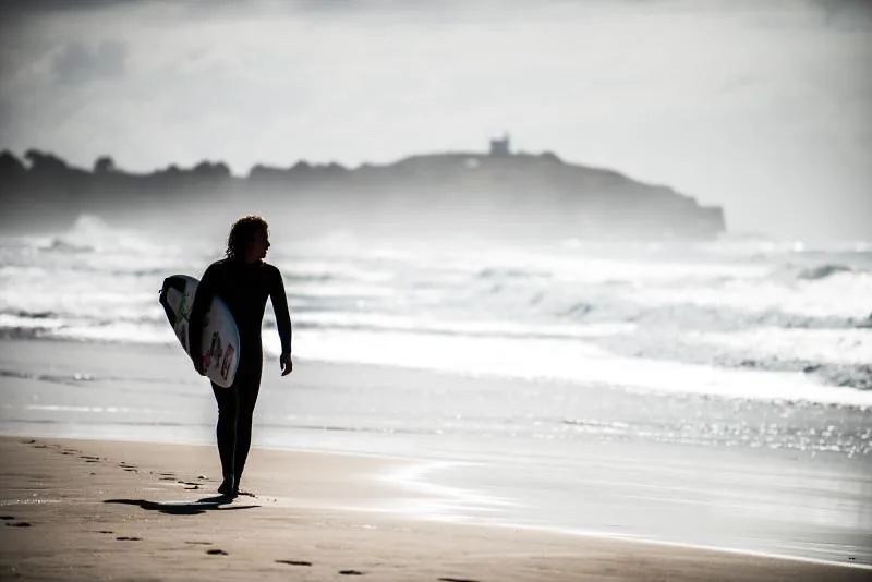 A surfer walking up the beach with his board, Australia