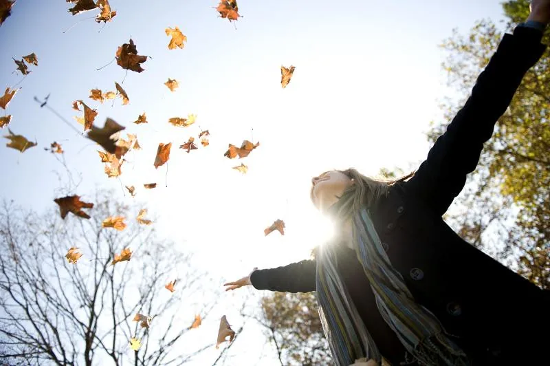A woman throwing autumn leaves into the air, Washington, D.C.